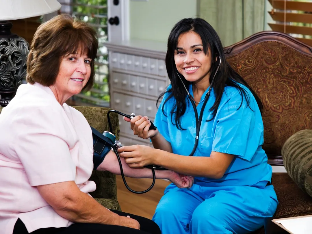 A caregiver taking an older woman's blood pressure